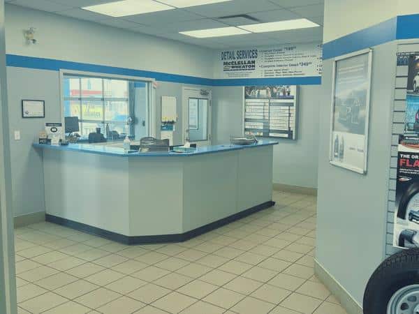 Auto service reception area with a blue counter, signage, and tire display on the right wall.