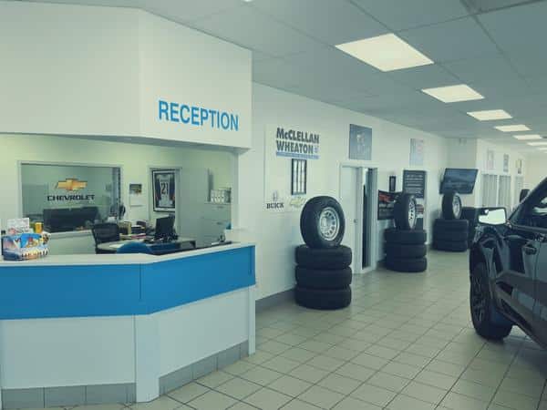 Car dealership reception area with tire stacks and visible branding signs.