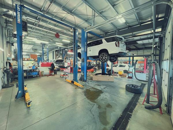 Auto repair shop with vehicles on lifts, mechanic tools, and workshop equipment visible.