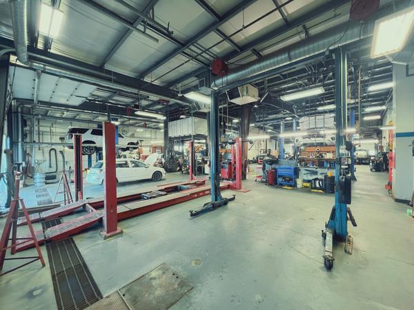 Auto repair shop interior with cars on lifts, tools, and equipment in a spacious garage setting.