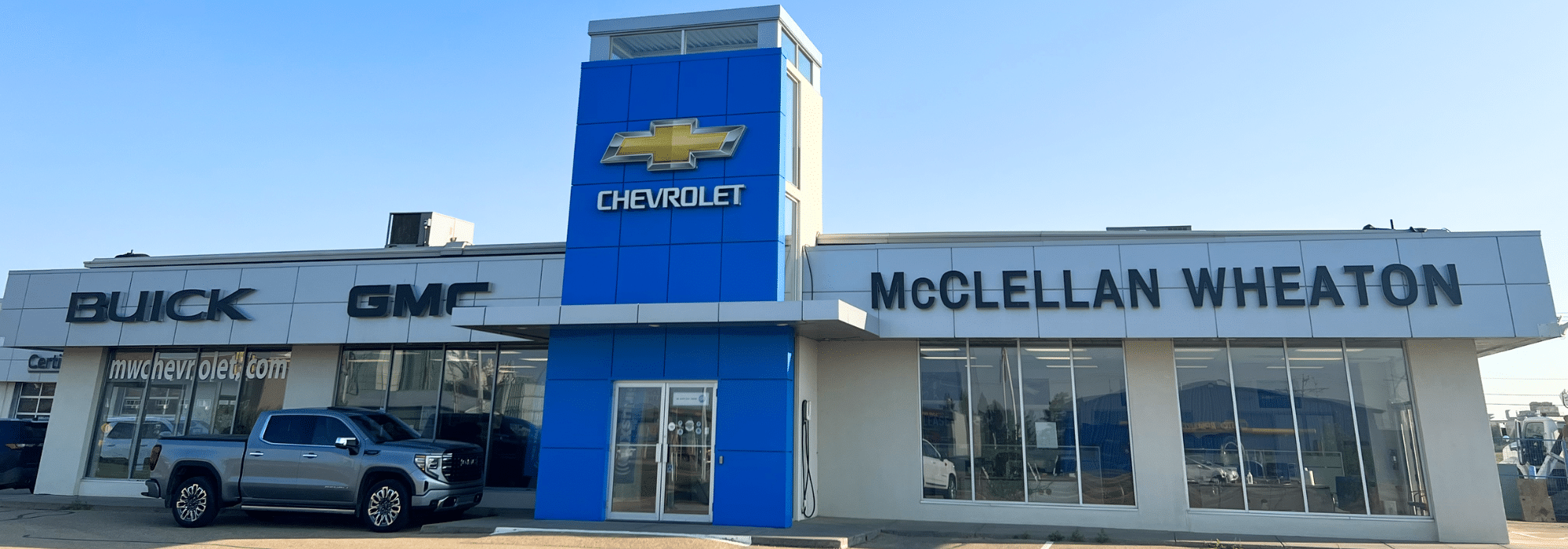 Exterior of McClellan Wheaton Chevrolet dealership featuring Buick and GMC signage with parked cars.