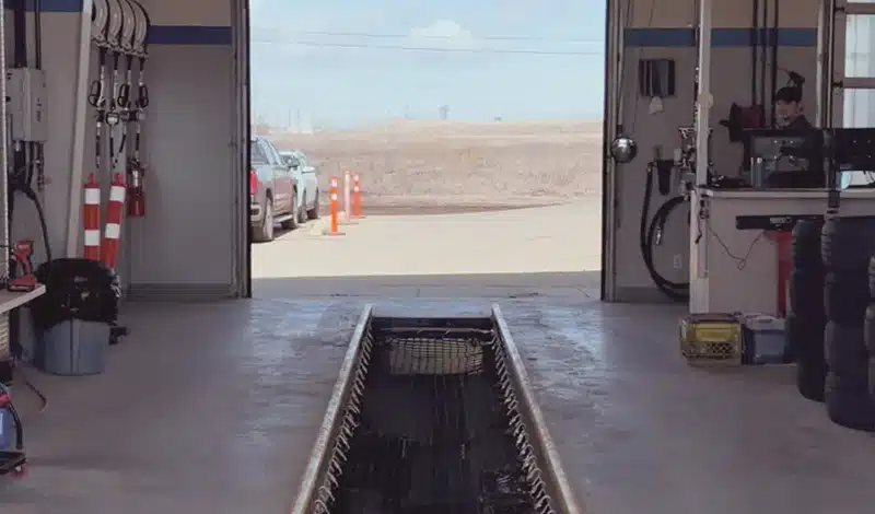 Car service garage with open bay, vehicle inspection pit, and exit sign above.